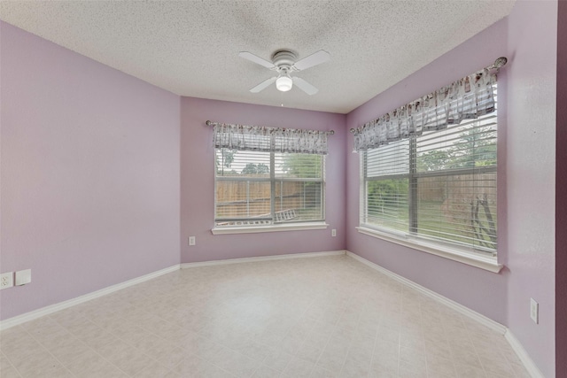 unfurnished room with baseboards, a textured ceiling, ceiling fan, and a wealth of natural light