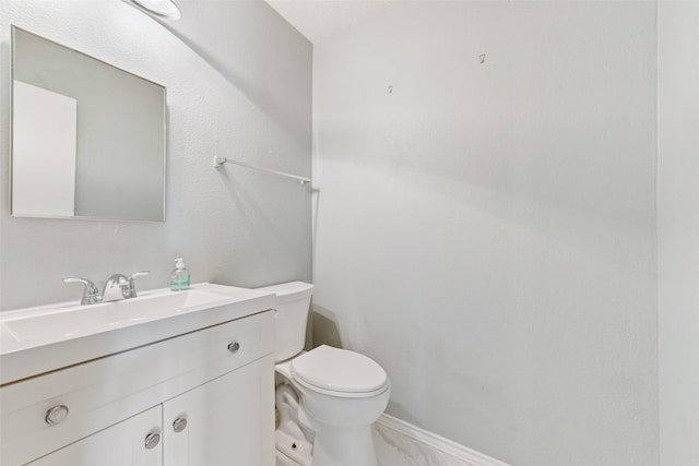 bathroom with toilet, marble finish floor, and vanity