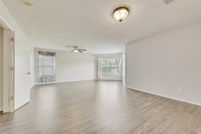 unfurnished room featuring baseboards, ceiling fan, a textured ceiling, and wood finished floors