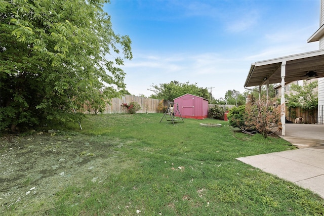 view of yard with fence, a ceiling fan, an outbuilding, and a shed