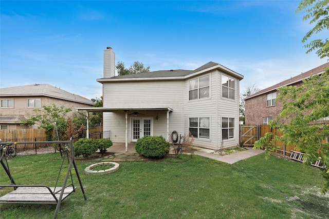 rear view of house with a fenced backyard, a chimney, a ceiling fan, a patio area, and a yard