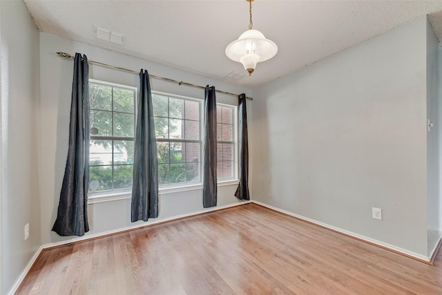 unfurnished room with baseboards, wood finished floors, and visible vents
