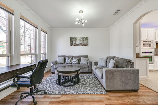 12165 Shoal Creek Dr, Frisco, TX 75035 - living room with arched walkways, healthy amount of natural light, ornamental molding, light wood-style floors, and a chandelier