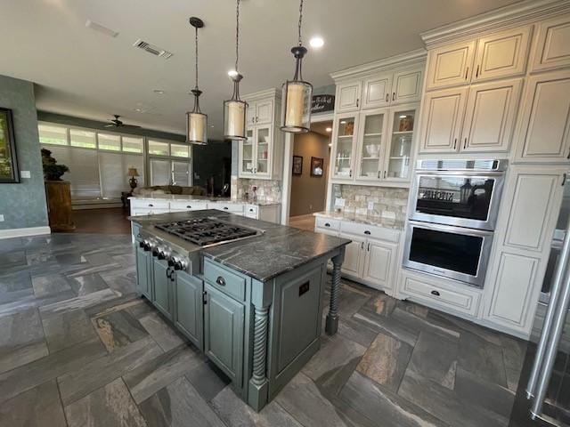 1900 Durance Ct, Corinth, TX 76210 - kitchen with decorative backsplash, glass insert cabinets, appliances with stainless steel finishes, visible vents, and a kitchen island