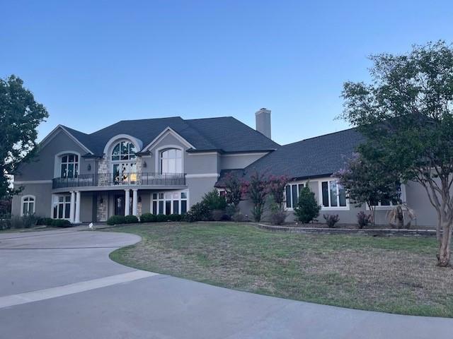 1900 Durance Ct, Corinth, TX 76210 - view of front of property with a front lawn, a chimney, stucco siding, and a balcony