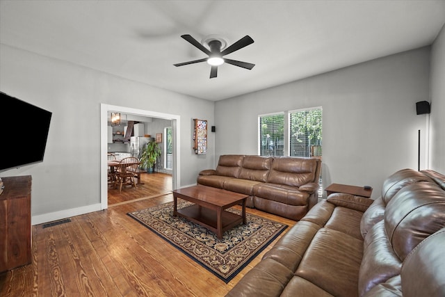 living area with wood finished floors, a ceiling fan, visible vents, and baseboards