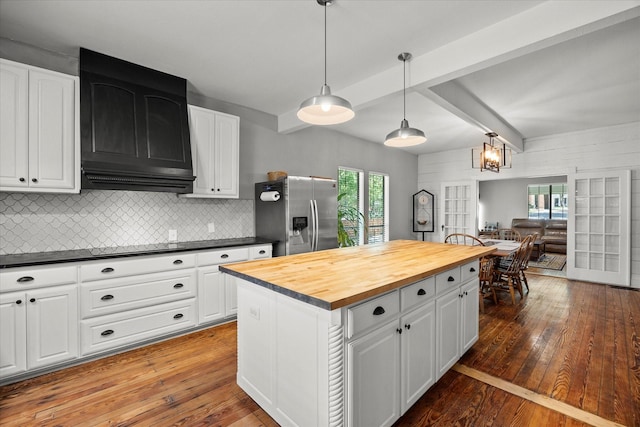 kitchen featuring exhaust hood, decorative backsplash, hardwood / wood-style floors, wooden counters, and stainless steel refrigerator with ice dispenser