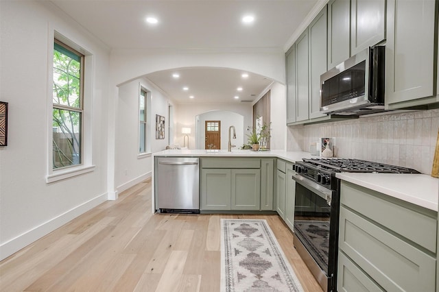 5105 Birchman Ave, Fort Worth, TX 76107 - kitchen featuring tasteful backsplash, arched walkways, green cabinetry, appliances with stainless steel finishes, and a peninsula