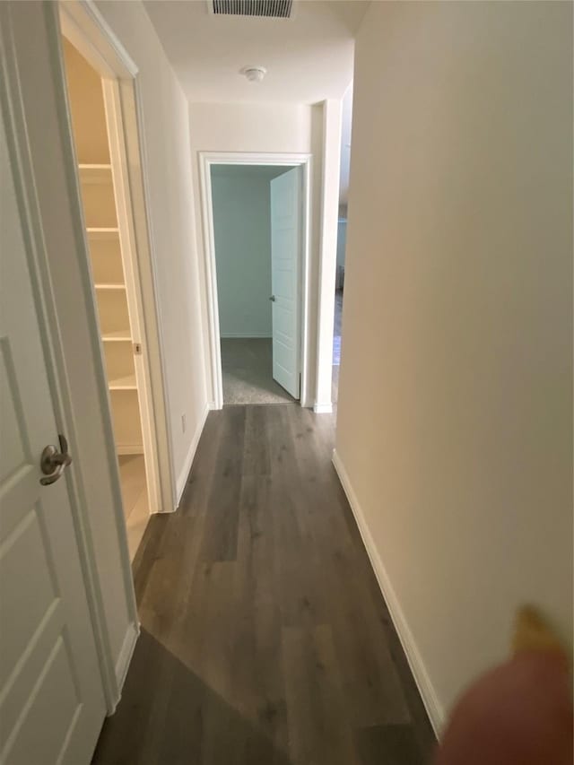 hall featuring dark wood finished floors, baseboards, and visible vents