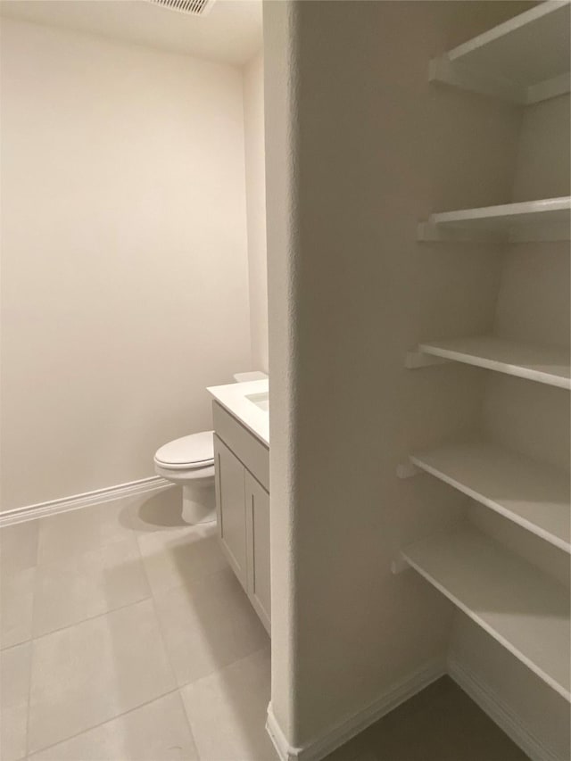 bathroom with toilet, vanity, tile patterned floors, and baseboards