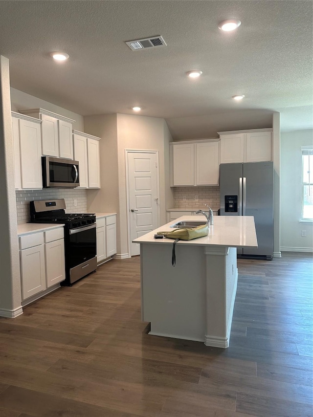 kitchen featuring decorative backsplash, a sink, visible vents, stainless steel appliances, and baseboards