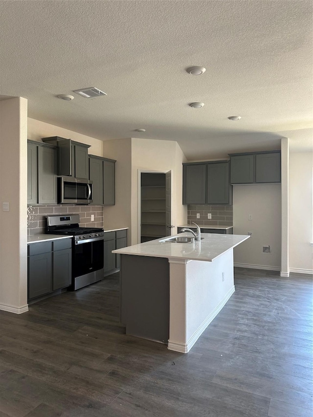 kitchen featuring dark wood-style floors, a sink, appliances with stainless steel finishes, and tasteful backsplash