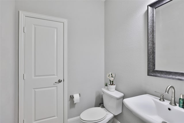bathroom featuring toilet, a sink, and baseboards