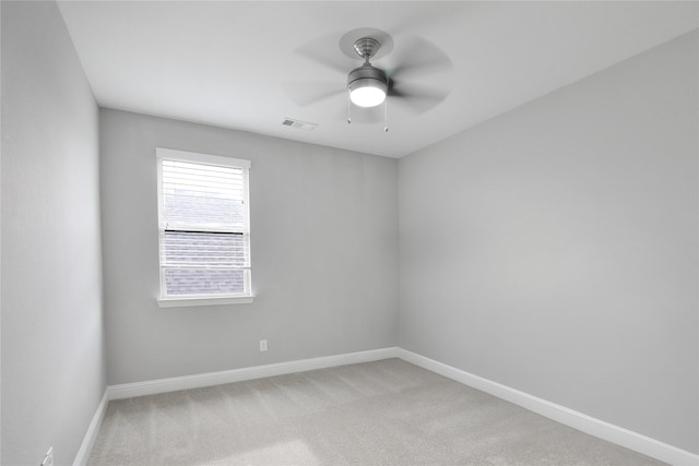 spare room with a ceiling fan, visible vents, light colored carpet, and baseboards