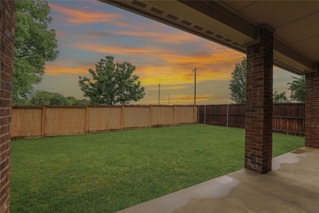 yard at dusk featuring a fenced backyard and a patio area
