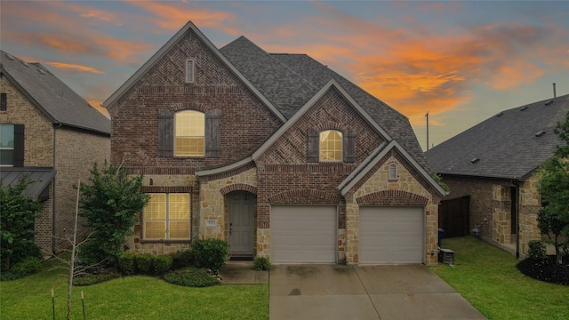 french country home with concrete driveway, stone siding, and brick siding