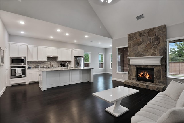 interior space featuring visible vents, a stone fireplace, dark wood-style flooring, and recessed lighting