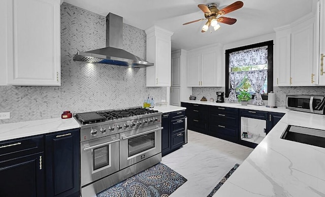 kitchen with dark cabinets, stainless steel appliances, white cabinets, ceiling fan, and wall chimney exhaust hood