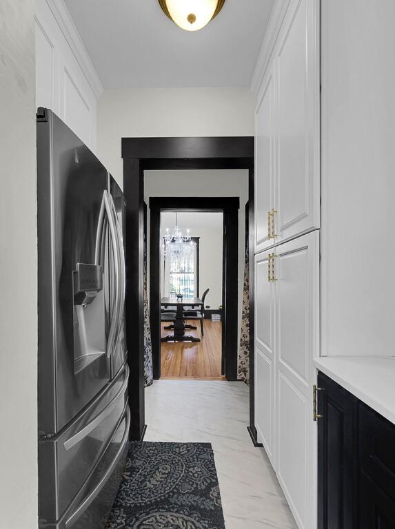 kitchen featuring white cabinetry, stainless steel fridge, light countertops, and an inviting chandelier