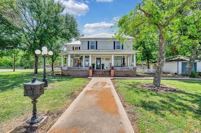 country-style home featuring covered porch, a front lawn, and metal roof