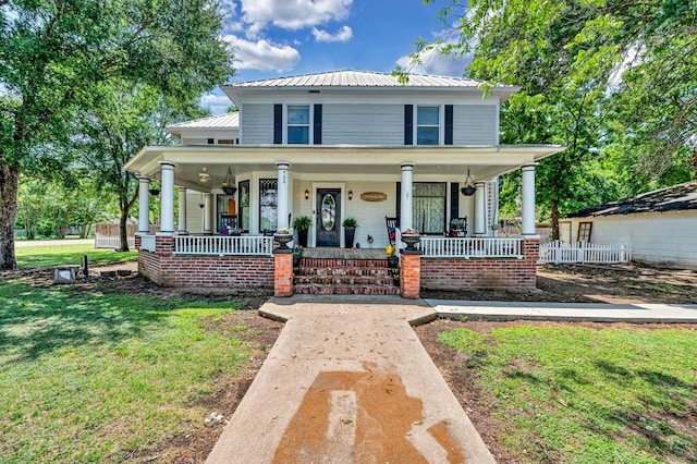 view of front facade featuring fence, a front yard, metal roof, and a porch