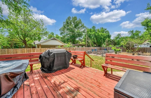 wooden terrace with area for grilling and a fenced backyard