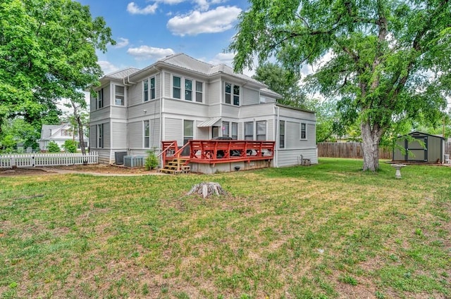 rear view of property with an outdoor structure, a storage unit, a deck, a lawn, and a fenced backyard