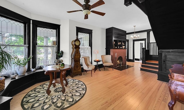 interior space with ceiling fan with notable chandelier and light wood-type flooring