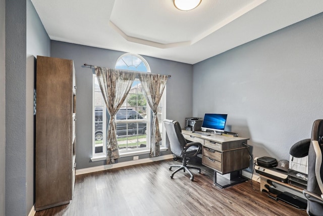 home office featuring a tray ceiling, wood finished floors, and baseboards