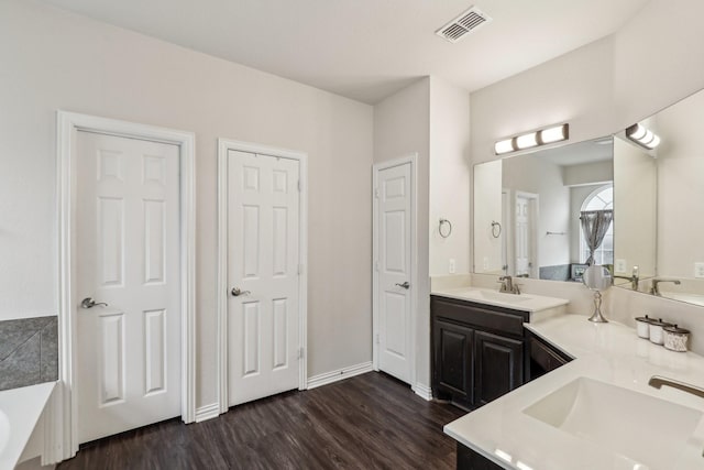 bathroom featuring double vanity, wood finished floors, visible vents, and a sink
