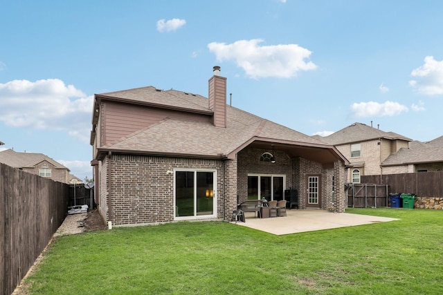 back of house featuring a chimney, a patio area, a lawn, brick siding, and a fenced backyard