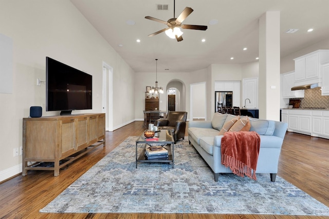living area with recessed lighting, visible vents, wood finished floors, and ceiling fan with notable chandelier