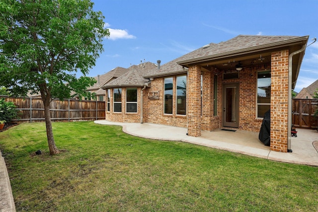 rear view of property with brick siding, a fenced backyard, a lawn, and a patio