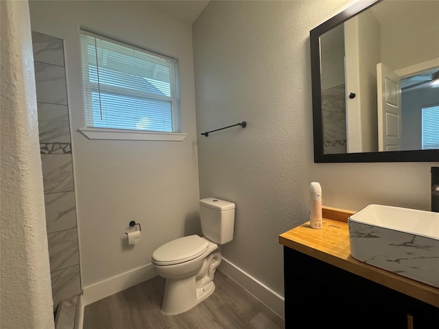 full bath with baseboards, wood finished floors, toilet, and vanity