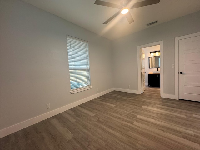 unfurnished bedroom featuring visible vents, baseboards, connected bathroom, and dark wood finished floors