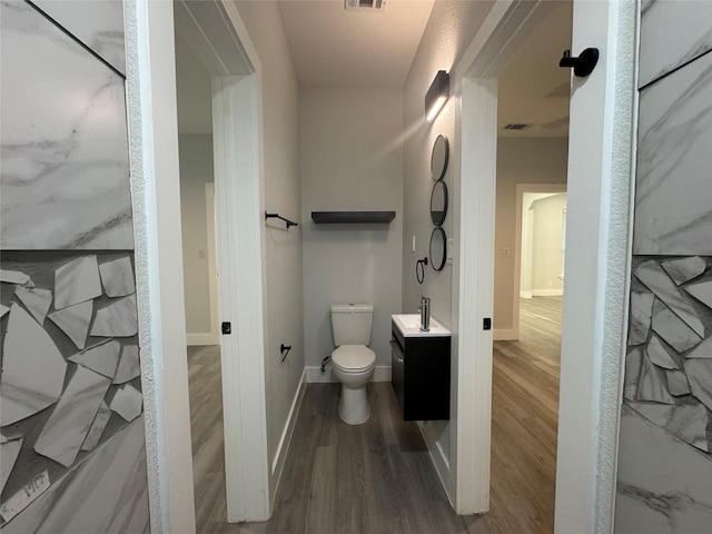 bathroom featuring wood finished floors, toilet, visible vents, and vanity
