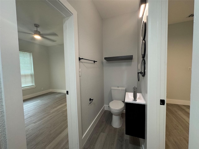 bathroom featuring toilet, a ceiling fan, wood finished floors, and baseboards