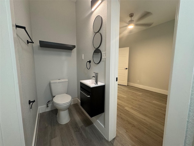 bathroom with wood finished floors, ceiling fan, toilet, vanity, and baseboards