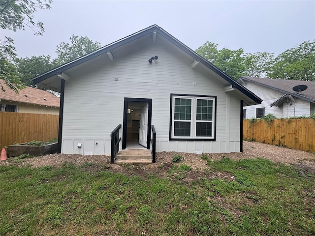 rear view of house featuring entry steps and fence
