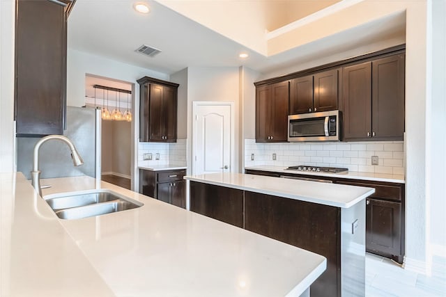 7955 Rasor Dr, Frisco, TX 75036 - kitchen with a sink, appliances with stainless steel finishes, dark brown cabinets, backsplash, and light countertops