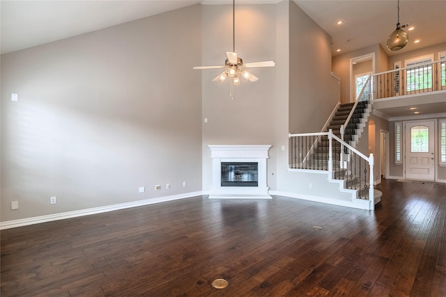 7955 Rasor Dr, Frisco, TX 75036 - unfurnished living room with a towering ceiling, stairway, dark wood finished floors, a glass covered fireplace, and ceiling fan