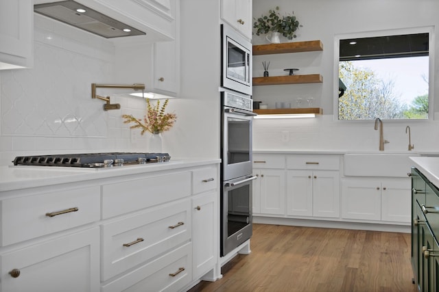 108 Grace View Rd, Weatherford, TX 76088 - kitchen featuring a sink, wall chimney exhaust hood, backsplash, light countertops, and appliances with stainless steel finishes