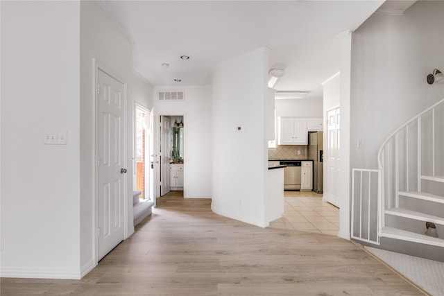 hall with crown molding, light wood finished floors, stairs, and visible vents