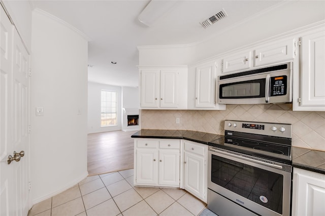 kitchen with visible vents, stainless steel appliances, dark countertops, and backsplash