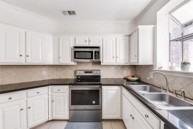 kitchen featuring appliances with stainless steel finishes, white cabinets, dark countertops, a sink, and visible vents