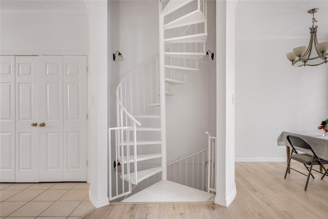 staircase featuring a chandelier, baseboards, and wood finished floors