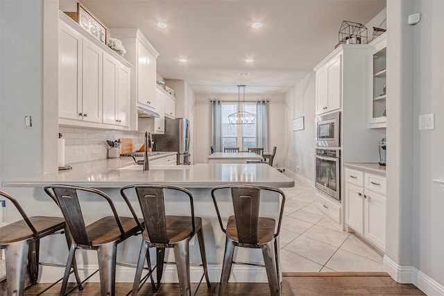 14733 Cedar Flat Way, Fort Worth, TX 76262 - kitchen featuring a breakfast bar area, stainless steel appliances, a peninsula, and white cabinetry