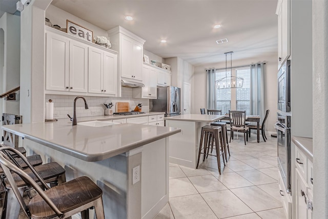 14733 Cedar Flat Way, Fort Worth, TX 76262 - kitchen with a sink, decorative backsplash, stainless steel appliances, under cabinet range hood, and a breakfast bar