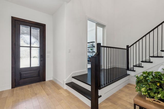 entryway with hardwood / wood-style floors, baseboards, and stairs
