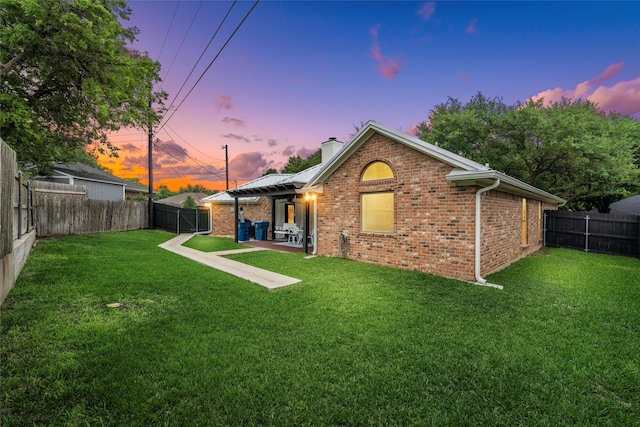 rear view of house with a lawn, a chimney, and a fenced backyard